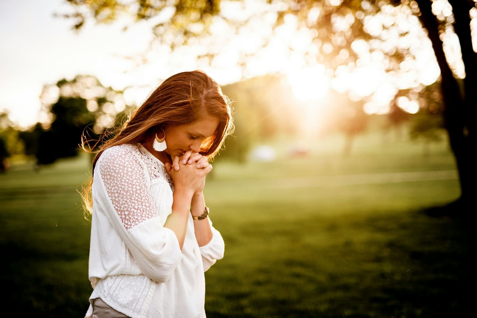 A woman praying outdoors at golden hour